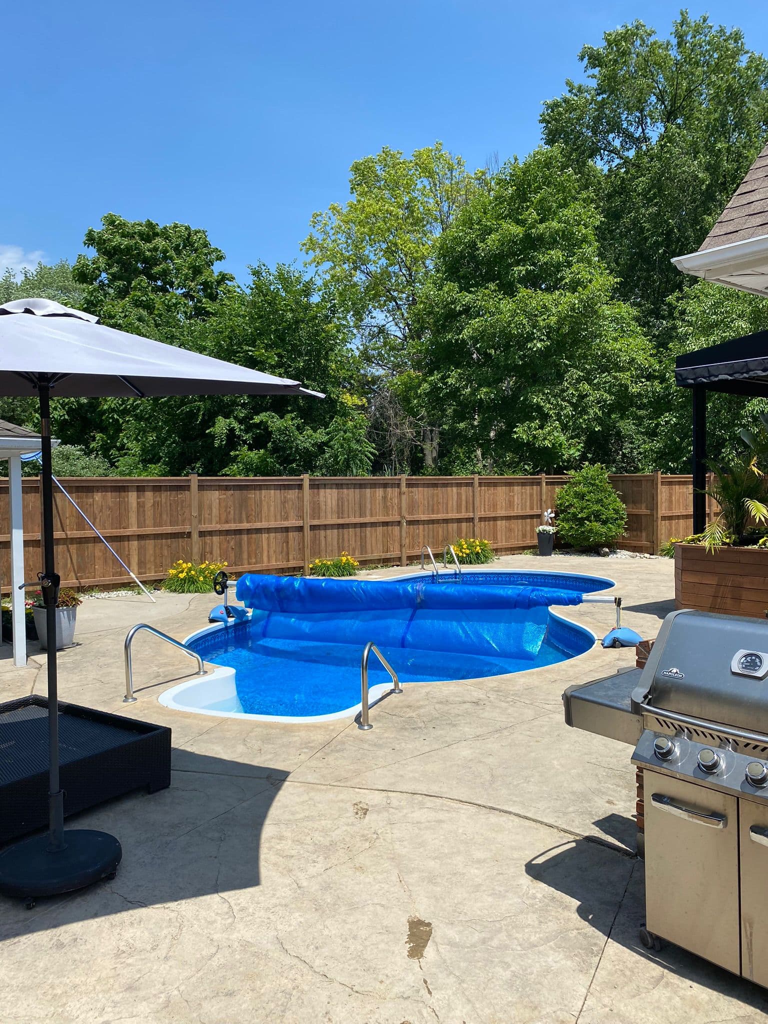 Wooden fence enclosing pool area with blue water and patio